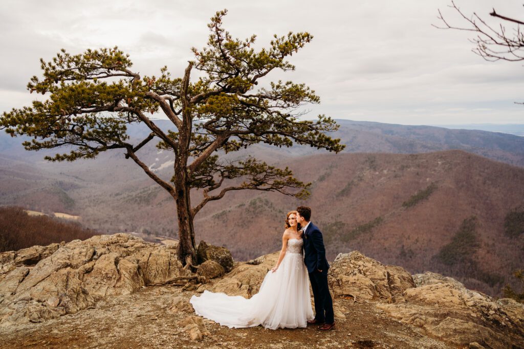 elopement couple standing beside tree at ravens roost overlook kissing