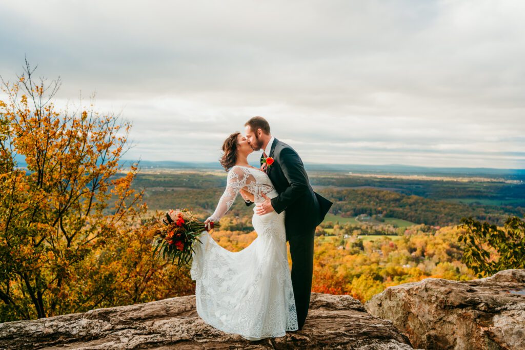 virginia-mountain-elopement-fall-overlook.jpg Bride and groom kiss on a rocky overlook surrounded by vibrant fall foliage in the Blue Ridge Mountains of Virginia during their elopement