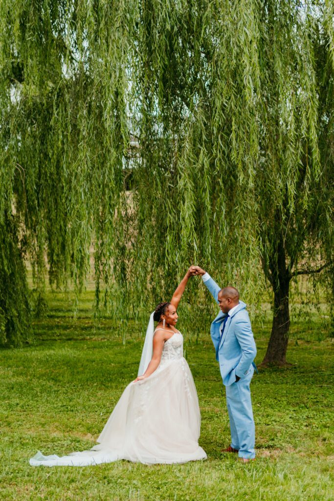 virginia-elopement-willow-tree-dance.jpg Bride twirls under a willow tree with her groom during their outdoor Virginia elopement