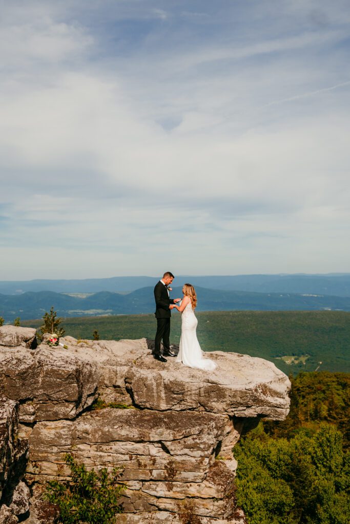 Bride and groom exchange vows on a dramatic cliff edge overlooking lush mountains during their adventurous West Virginia elopement in Dolly Sods West Virginia.