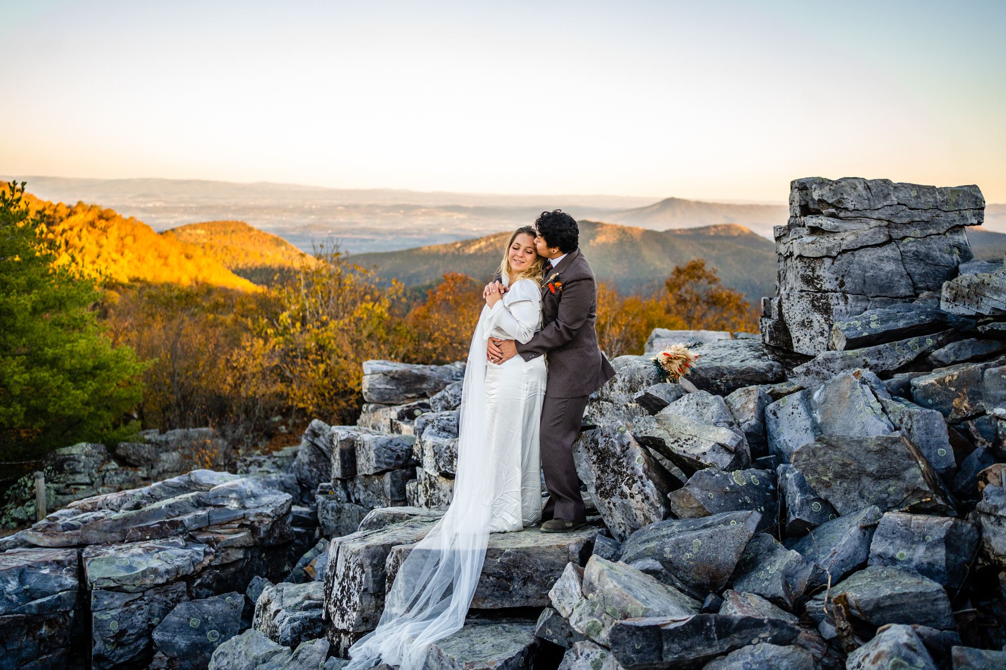 Groom hugging bride from behind on mountaintop during romantic fall Shenandoah elopement.