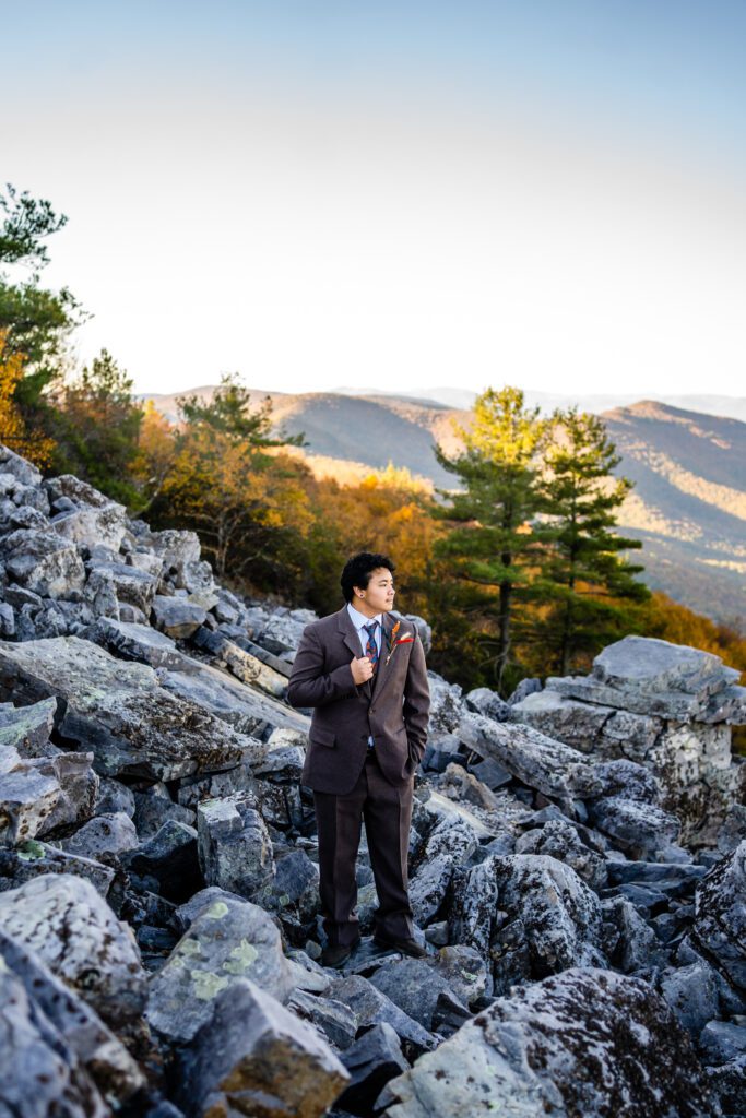 Groom standing on rocky overlook during fall elopement in Shenandoah National Park with Blue Ridge Mountains in the background.