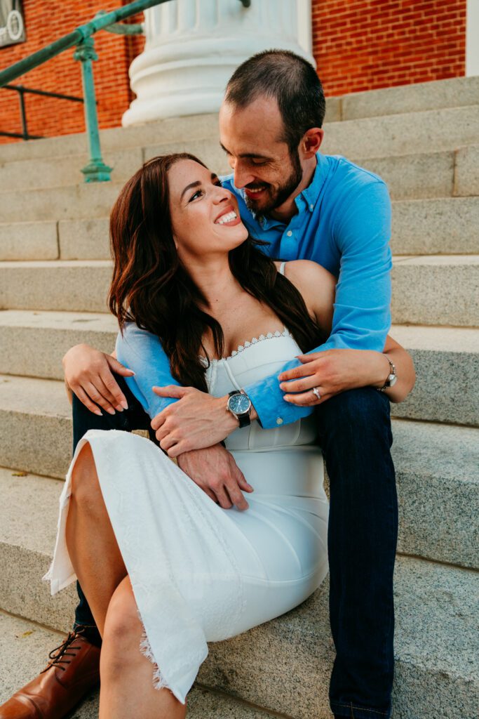 Romantic engagement photo of couple sitting on courthouse steps in downtown Frederick MD