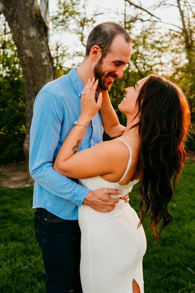 Candid moment of couple smiling and leaning in close during sunset engagement session in Frederick MD
