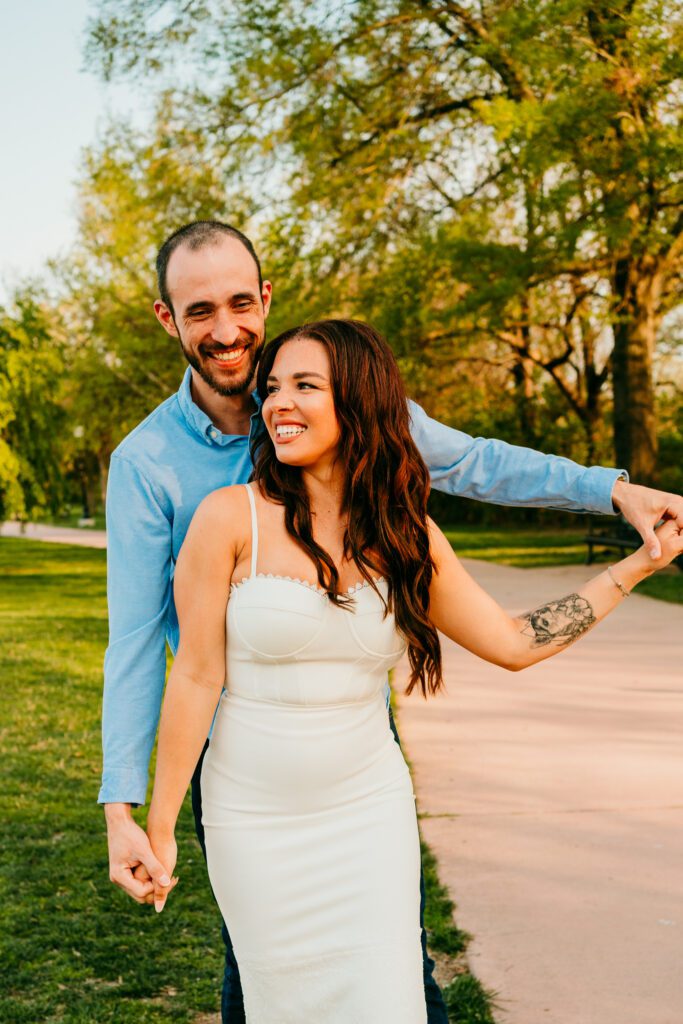 Playful moment of couple holding hands and laughing during engagement session in Baker Park Frederick MD