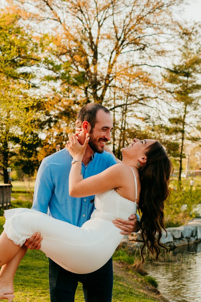 Groom lifting bride as they laugh during their engagement session in Frederick MD near Baker Park